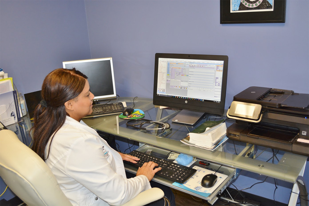 a focused vet in a white lab coat working at a desk with a computer